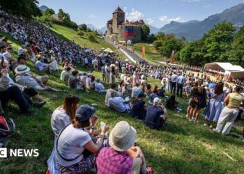 Hundreds of people gather on the slopes below Vaduz Castle, the palace and official residence of the Prince of Liechtenstein, during its National Day celebrations in Vaduz, on 15 August. Mountains can be seen in the background.