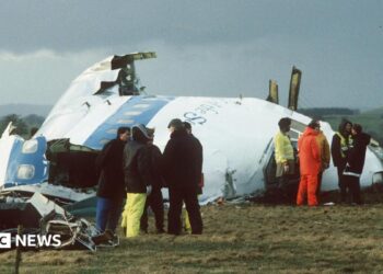 Emergency service workers stand next to the wreckage of Pan Am flight 103 in a field east of Lockerbie.