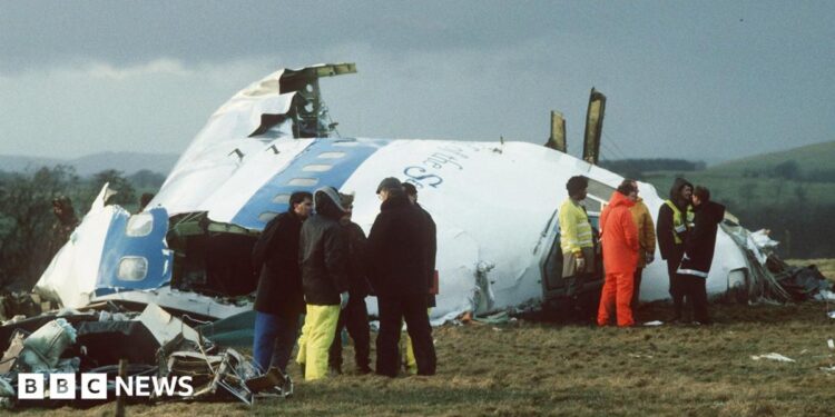 Emergency service workers stand next to the wreckage of Pan Am flight 103 in a field east of Lockerbie.