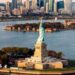 aerial shot of Statue of Liberty and waters surrounding it with New York skyline in background