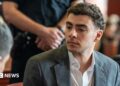 Luigi Mangione wears a charcoal grey suit as he sits in court for a recent state hearing.