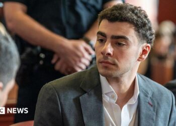 Luigi Mangione wears a charcoal grey suit as he sits in court for a recent state hearing.