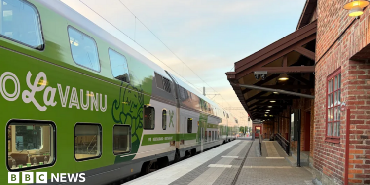 A blue train with Lumo branding travelling under overhead wires.