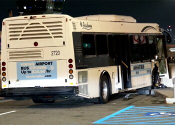 shuttle bus rests against a concrete barrier after the crash