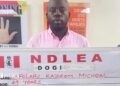 Afolabi Kazeem Micheal holds up a NDLEA sign with his name and age after his arrest in Lagos