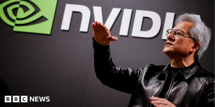 Nvidia CEO Jensen Huang standing in front of a screen with the company's name and logo, gesturing upward with his hands, wearing a black leather jacket over a black shirt.