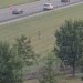 Highway camera view of a person running across a grassy field beside a multi-lane interstate with passing traffic.