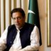 Former Pakistani Prime Minister Imran Khan speaks with Reuters during an interview, in Lahore, Pakistan March 17, 2023. He can be seen seated with his hand outstretched and speaking. Two Pakistani flags are behind him.