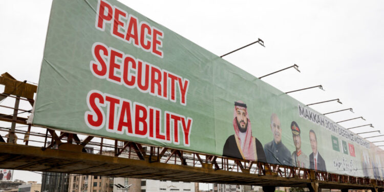 Billboard displays leaders following the signing of the Makkah Joint Defence Agreement, in Karachi