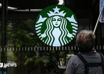 A cleaning lady wipes the window of a Starbucks coffee shop