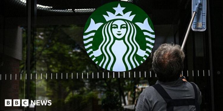 A cleaning lady wipes the window of a Starbucks coffee shop