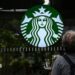 A cleaning lady wipes the window of a Starbucks coffee shop