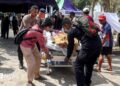 Police officers help move a patient to an open-area shelter at a hospital, following an earthquake felt in Labuan Bajo, East Nusa Tenggara province