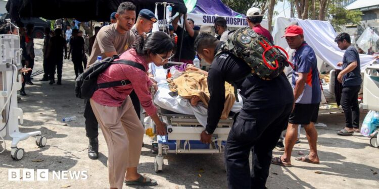 Police officers help move a patient to an open-area shelter at a hospital, following an earthquake felt in Labuan Bajo, East Nusa Tenggara province