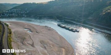 An aerial view as a cargo ship passes a huge exposed sandbar on the Rhine River