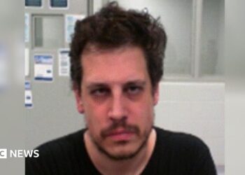 DHS released an mugshot of Yiannopoulos after his arrest. He wears a black shirt and has facial hair