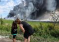People watch as smoke rises above a Wildberries facility following a reported Ukrainian drone strike at the Koledino Industrial Park near Podolsk in Russia on 16 August.