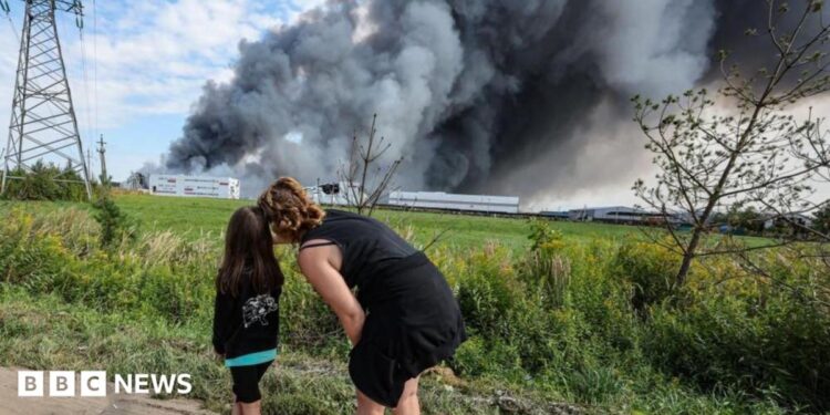 People watch as smoke rises above a Wildberries facility following a reported Ukrainian drone strike at the Koledino Industrial Park near Podolsk in Russia on 16 August.
