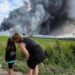 People watch as smoke rises above a Wildberries facility following a reported Ukrainian drone strike at the Koledino Industrial Park near Podolsk in Russia on 16 August.