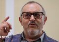 Boris Nadezhdin, who has short grey hair, wears a colourful blazer and glasses in court in Dolgoprudny, Moscow region, last month. He is pointing upwards with his right index finger.