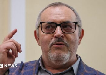 Boris Nadezhdin, who has short grey hair, wears a colourful blazer and glasses in court in Dolgoprudny, Moscow region, last month. He is pointing upwards with his right index finger.