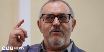 Boris Nadezhdin, who has short grey hair, wears a colourful blazer and glasses in court in Dolgoprudny, Moscow region, last month. He is pointing upwards with his right index finger.