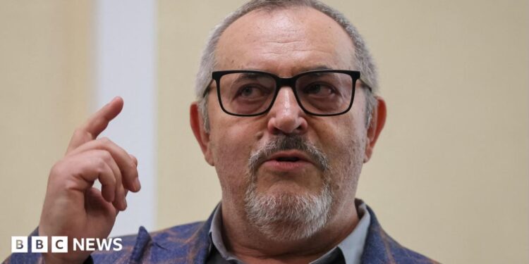 Boris Nadezhdin, who has short grey hair, wears a colourful blazer and glasses in court in Dolgoprudny, Moscow region, last month. He is pointing upwards with his right index finger.