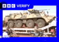 A Russian military vehicle being transported through the Malian capaitl, Bamako. Men on motorcycles are riding alongside it.