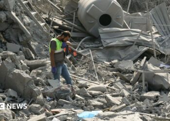 An emergency worker looks through rubble in the aftermath of an airstrike on Ansar in Lebanon