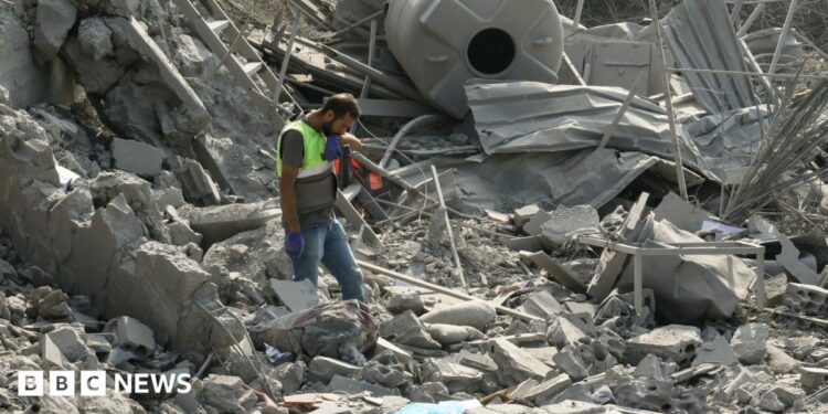 An emergency worker looks through rubble in the aftermath of an airstrike on Ansar in Lebanon
