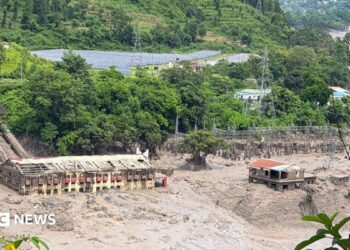Mud and sand are piled up against a hydropower plant affected by a flash flood in northern Nepal