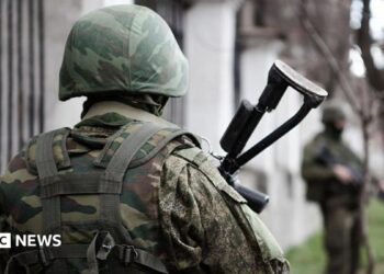 An unidentifiable Russian soldier stands with his back to the camera