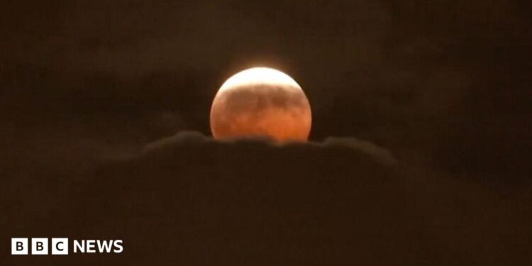 The Moon has a red tinge as it rises above clouds during the partial eclipse over Anaheim, California
