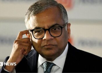 N Chandrasekaran, wearing a dark suit, white shirt and thick-rimmed glasses, touches his ear in this photo taken at the Bombay Stock Exchange in Mumbai, India, on November 12, 2025.