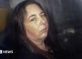 Erin Patterson, looking at the camera in the back of a prison van