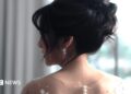 A bride with her in an updo looks over her shoulder.