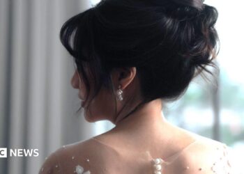 A bride with her in an updo looks over her shoulder.