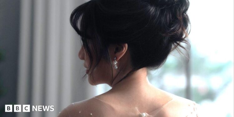A bride with her in an updo looks over her shoulder.