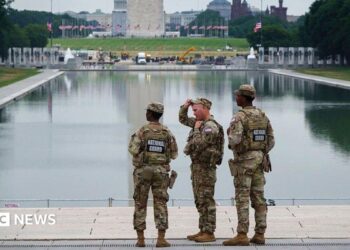 Three members of the National Guard stand in front of the Reflecting Pool