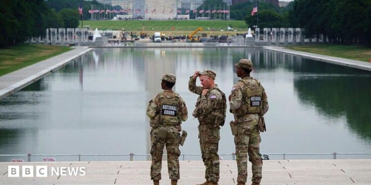 Three members of the National Guard stand in front of the Reflecting Pool