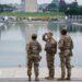 Three members of the National Guard stand in front of the Reflecting Pool