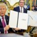 US President Donald Trump holds up a document with his signature in the Oval Office. Begin him is Secretary of the Interior Doug Burghum and a large map showing the US and Canada and the Great Lakes, with Lake Ontario renamed in red script as Lake America.