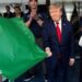 Donald Trump waves a green flag as he stands next to his wife Melania who is smiling and clapping