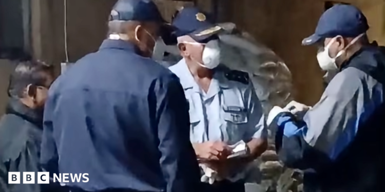 Three officers in face masks and uniform in discussion during a raid on a meth lab found at a farm in Limpopo province