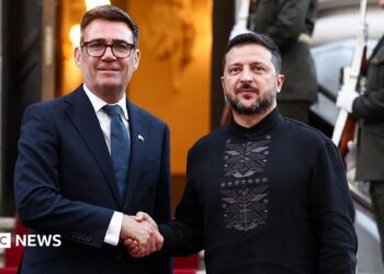 Burnham and Zelensky pose looking at the camera while shaking hands with soldiers behind them, on the steps of Horodetskyi House in Kyiv on Monday.