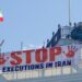 Protesters hold a banner saying "stop executions in Iran" and wave an Iranian flag during a demonstration on the roof of the Trocadero, overlooking Piccadilly Circus, central London (30 July 2026)