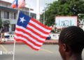 A back view of person holding a small Liberian flag on a street in Monrovia
