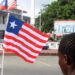 A back view of person holding a small Liberian flag on a street in Monrovia