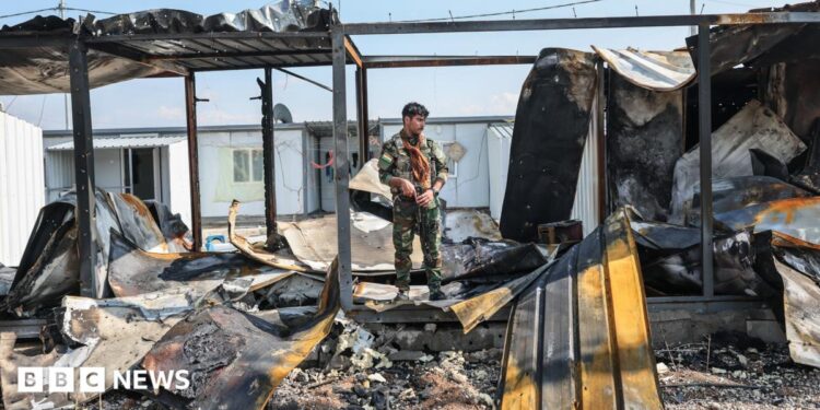 A member of Kurdistan Freedom Party stands next to damaged containers at their military base in Irbil, Iraq, after Iranian drone attack in March