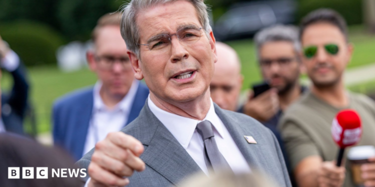 US Treasury Secretary Scott Bessent addresses members of the media on the lawn outside the White House. He's wearing a light grey suit, white shirt and silver tie